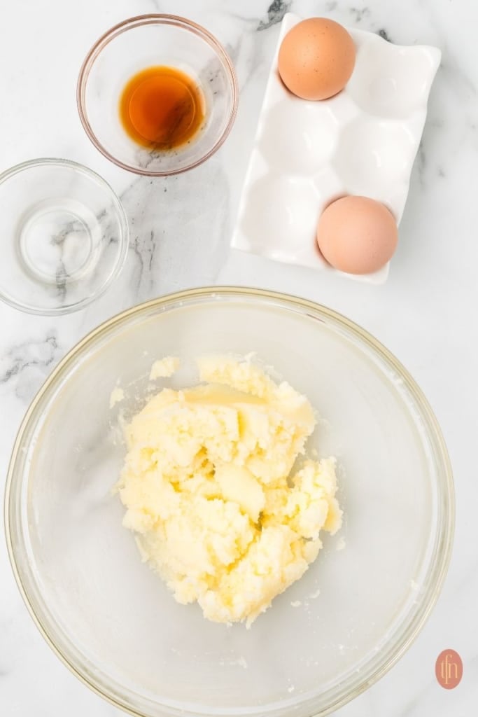 a mixture of a dough with a bowl of vanilla extract, peppermint extract and eggs at the top.