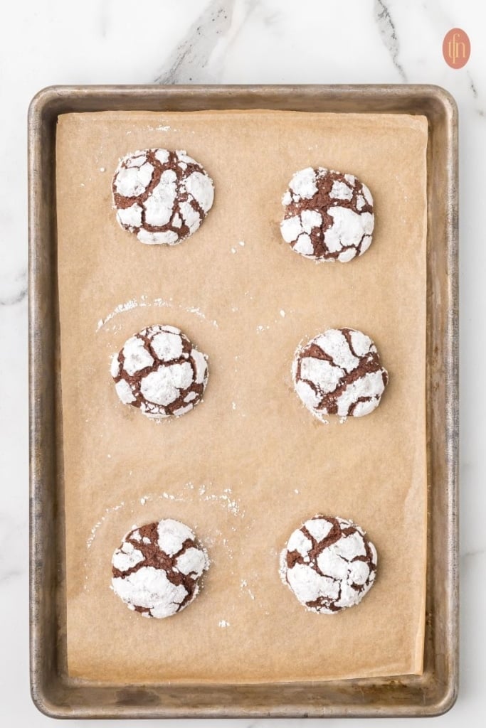 cooling Christmas crinkle cookies in the baking sheet.