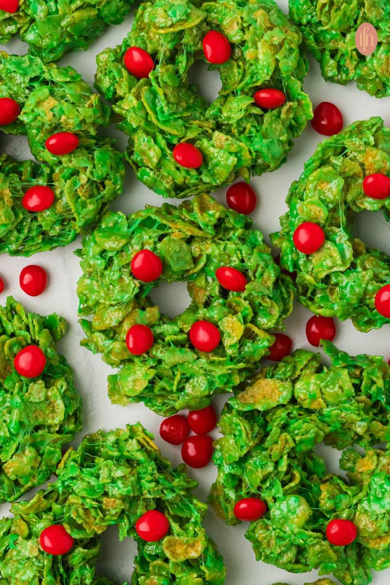 an image of cornflake wreath cookies with red cinnamon candies on top.