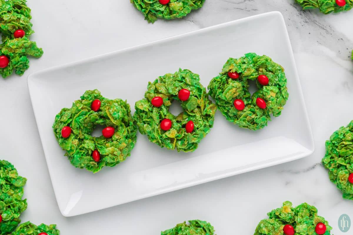 a plate of cookies with cornflakes and a red cinnamon candies on top of it.