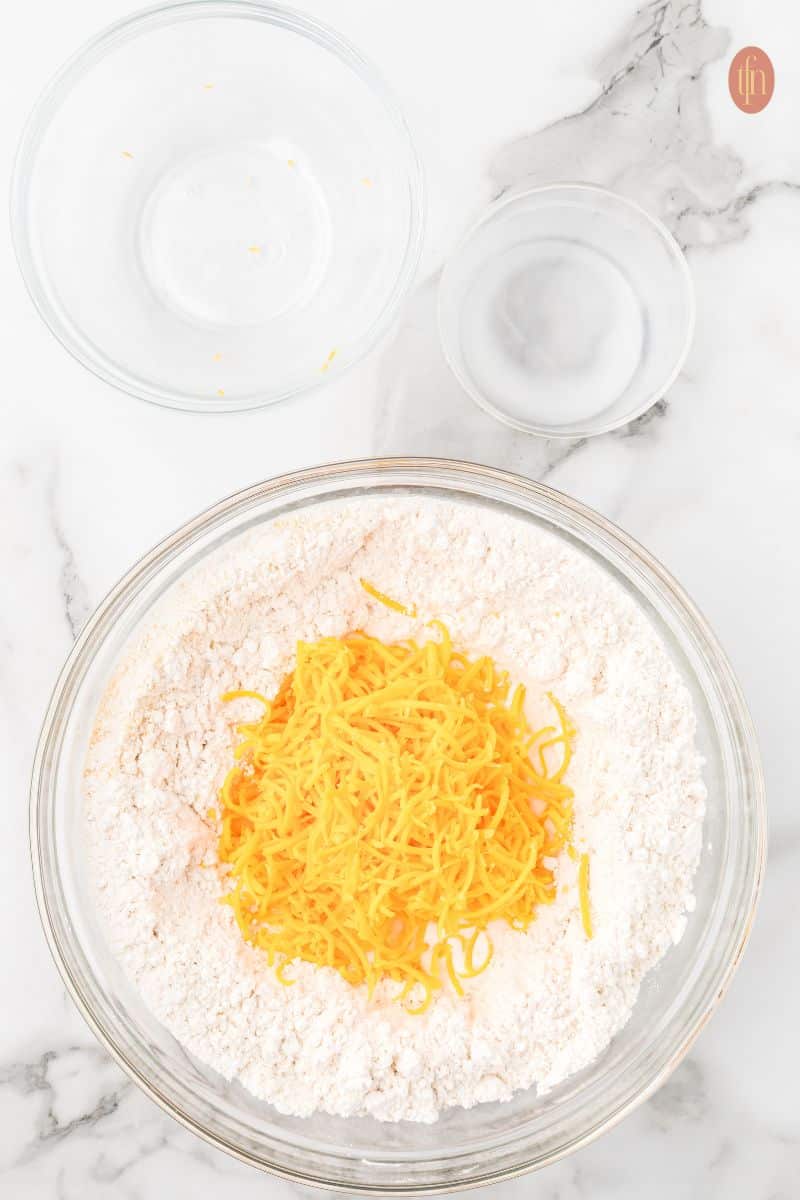 A bowl with dry ingredients and shredded cheese.