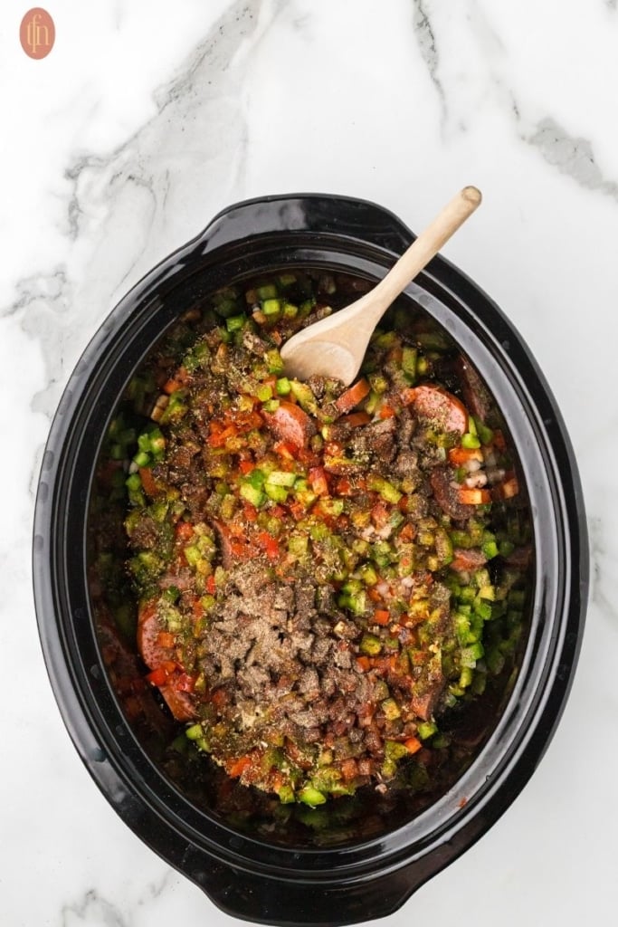 a full crockpot with ingredients for sausages and potatoes in slow cooker.
