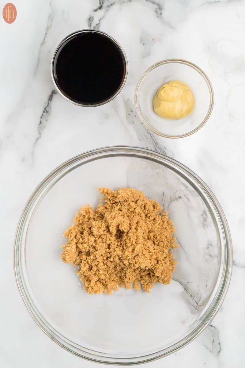 a bowl of brown sugar with a small bowl of coca cola and dijon mustard on the side.