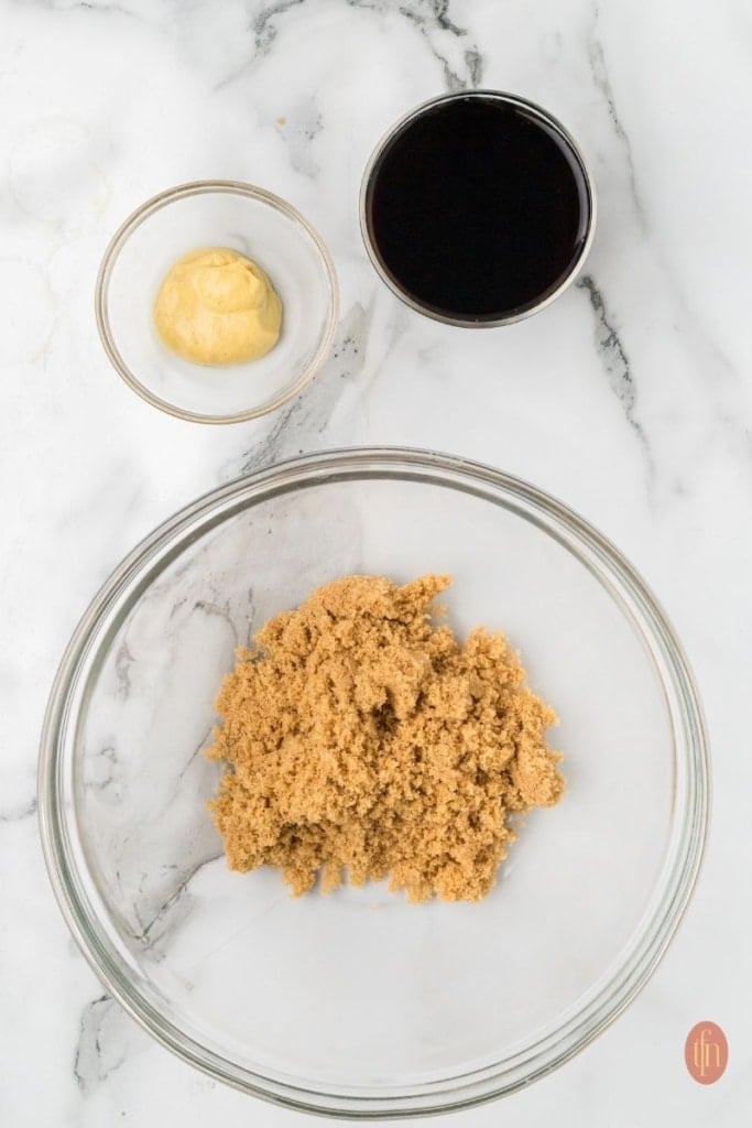 a bowl of brown sugar with a small bowl of coca cola and dijon mustard on the side.