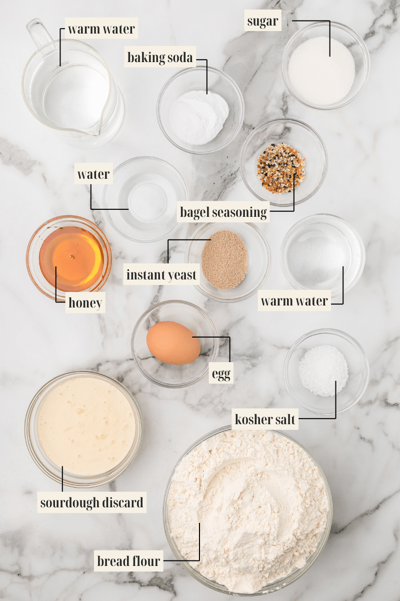 all the ingredients for sourdough bagels in small glass bowls.