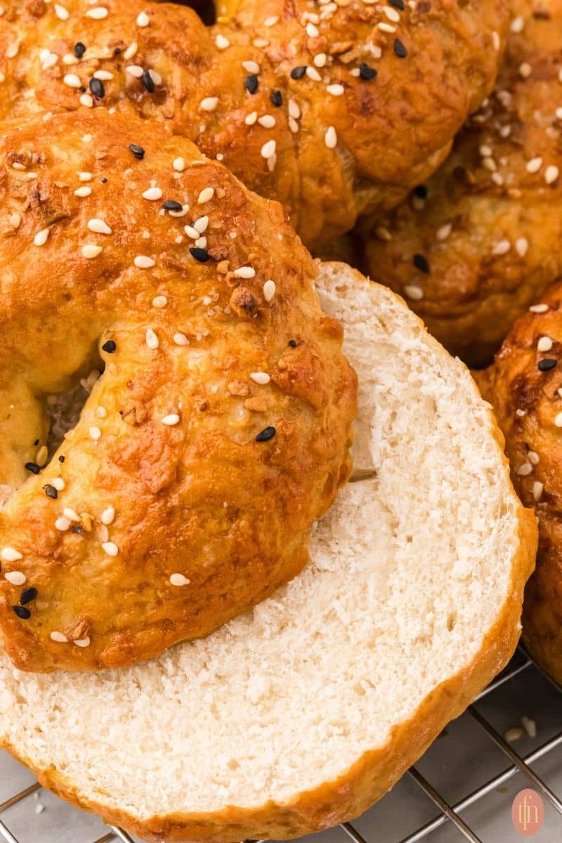 an image of sourdough bagels cut in half with other bagels in the background.