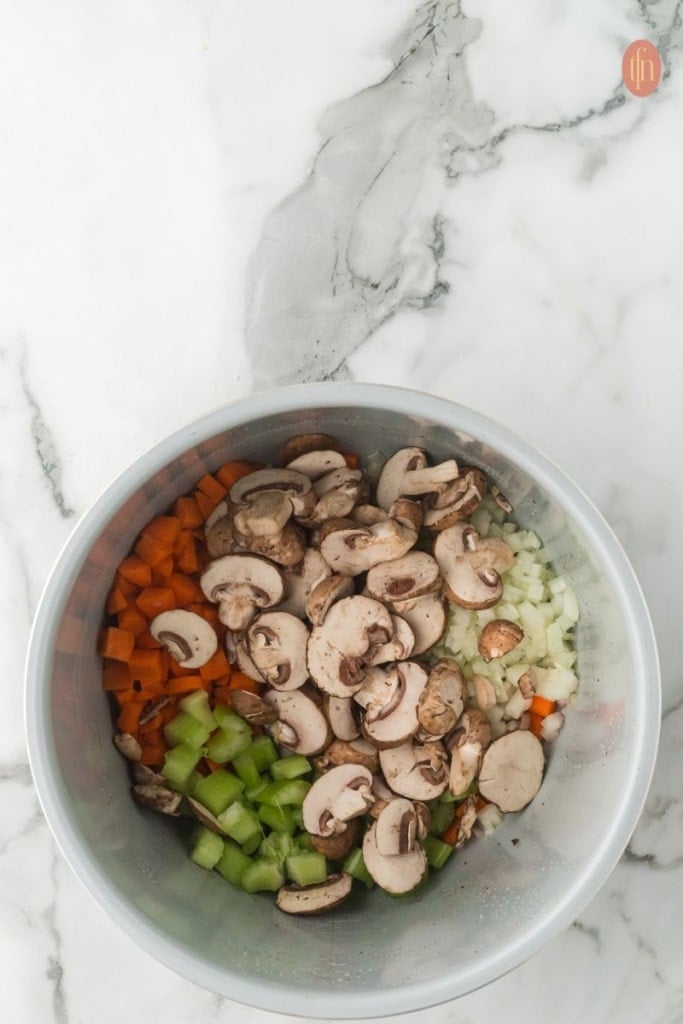 a pot of vegetables ready to saut&eacute;: carrots, celery, mushrooms and onion.