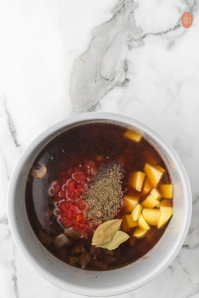a pot of saut&eacute;ed vegetables, browned beef, potatoes, and Worcestershire sauce with black pepper, dried thyme, and bay leaves.