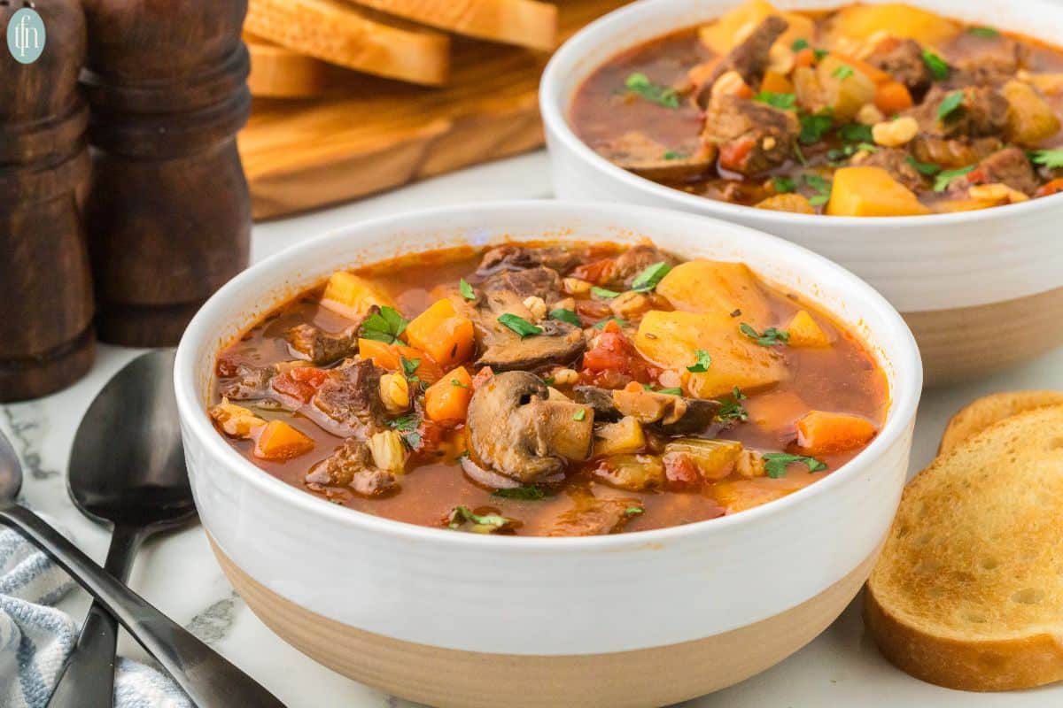 a close up shot of instant pot beef and barley soup in a bowl.