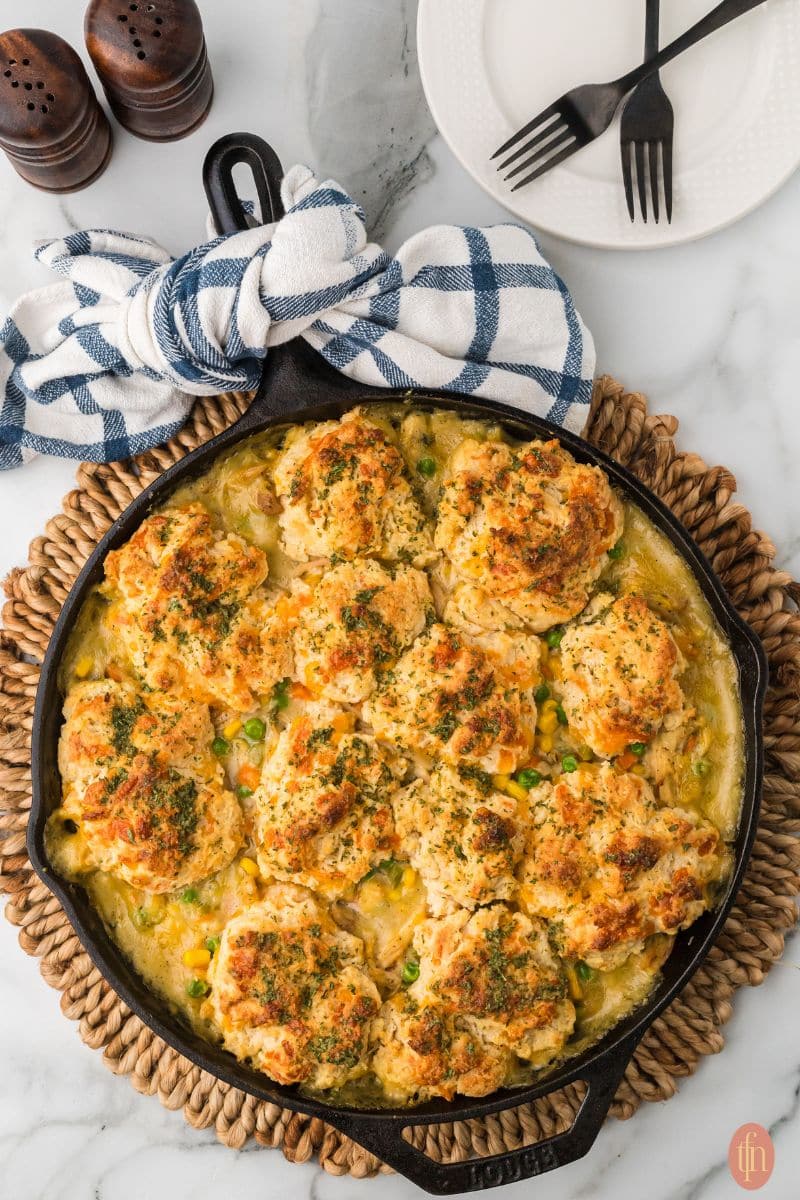 chicken pot pie with biscuit topping in a black cast iron skillet.