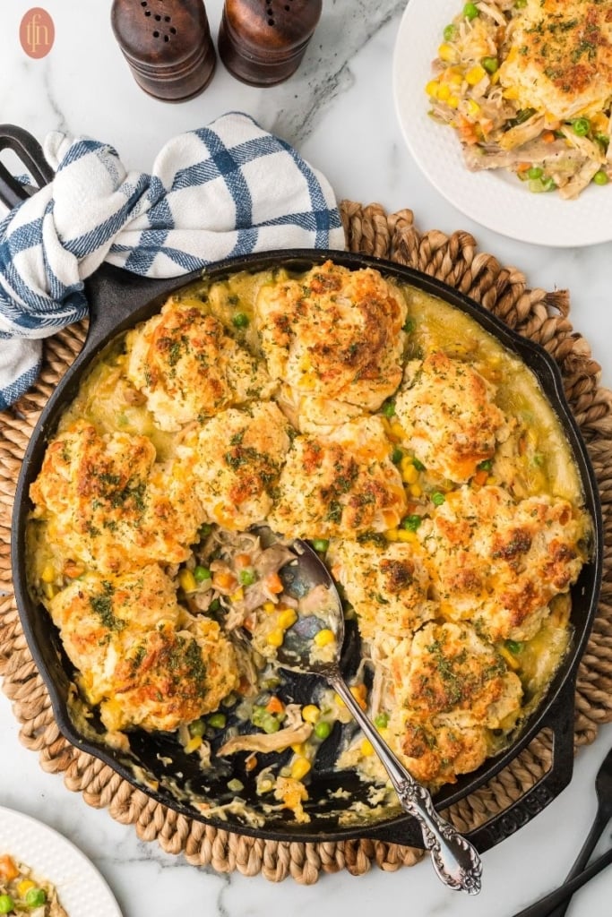 chicken pot pie with biscuit topping in a black cast iron skillet.