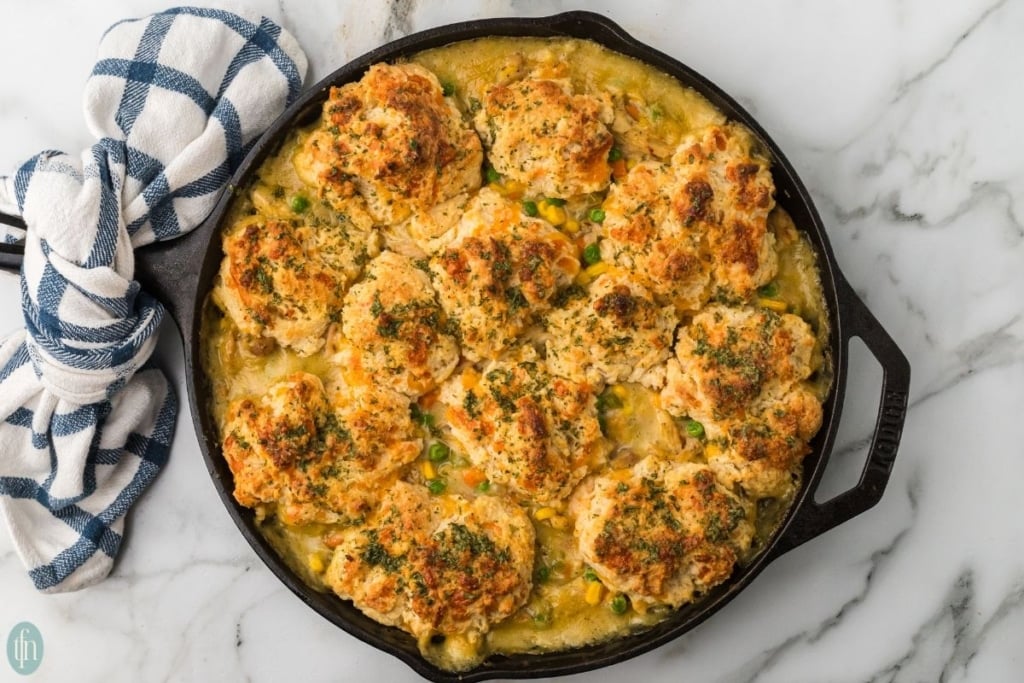 chicken pot pie with biscuit topping in a black cast iron skillet.