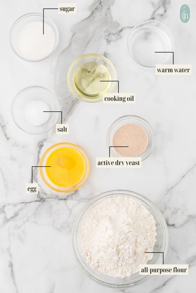 quick pizza dough ingredient image: sugar, salt, cooking oil, warm water, salt, egg, active dry yeast and all purpose flour.