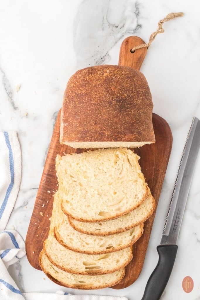 sliced sourdough sandwich bread on a wooden board.