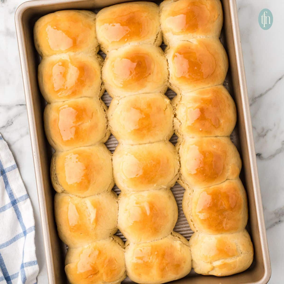 freshly baked golden dinner rolls in a baking tray.