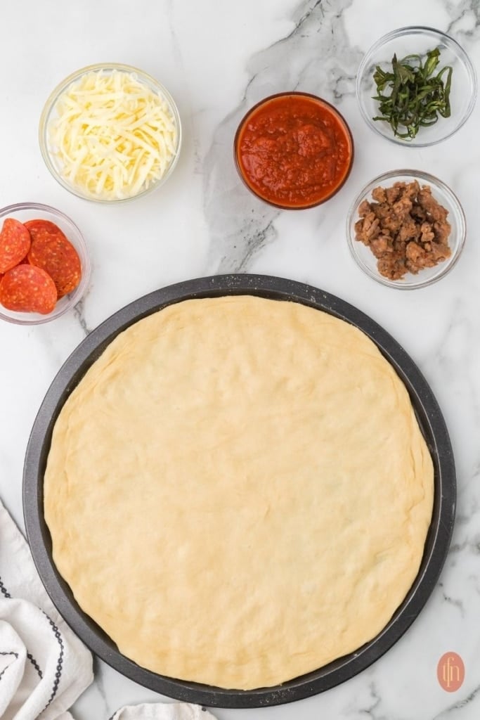 a pizza dough and other pizza toppings on the side.