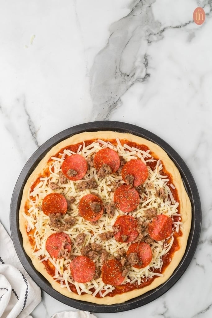 pizza topped with pepperonis, sausage and cheese served on a black circular pan.