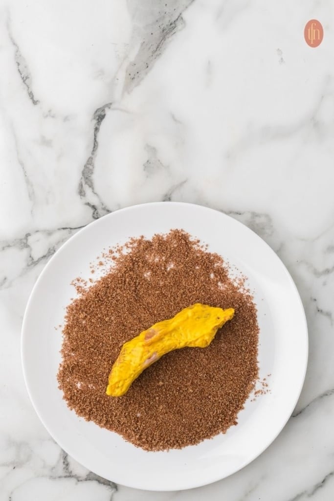 a plate of a piece of baby back rib with mustard and seasoning.