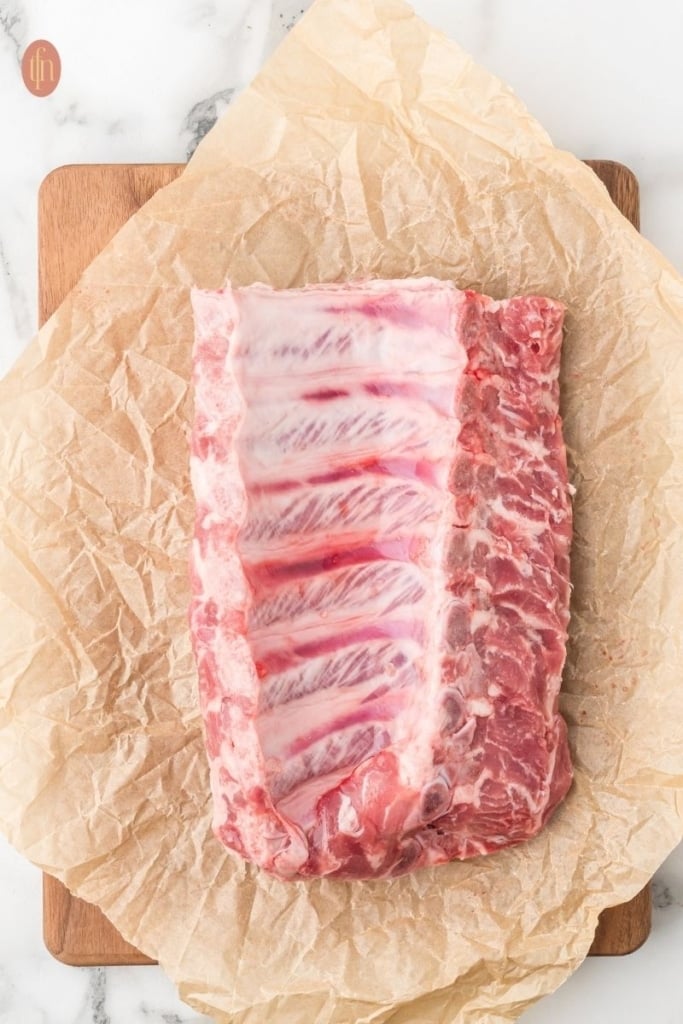 a raw pork ribs on a sheet of parchment paper.