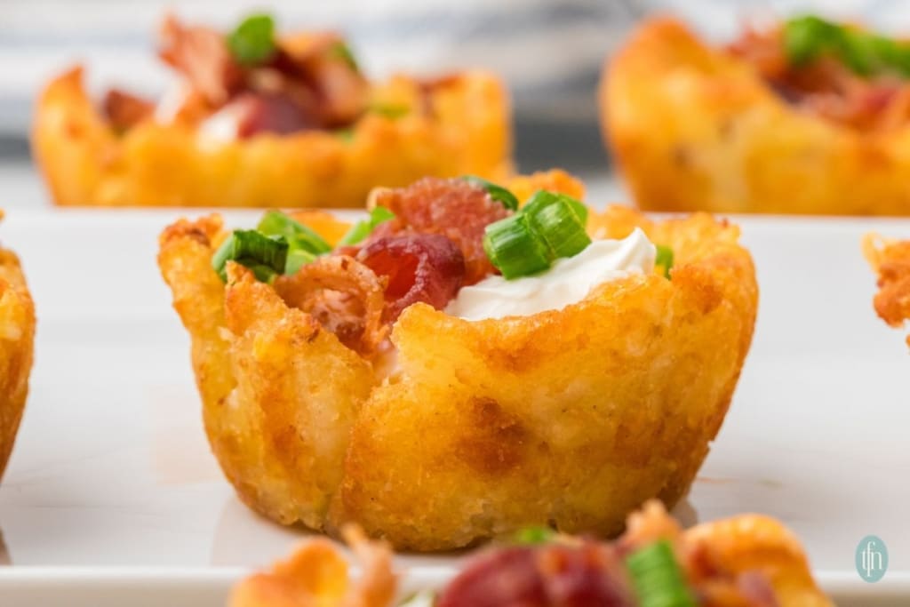 a close up shot of loaded tater tot cups.