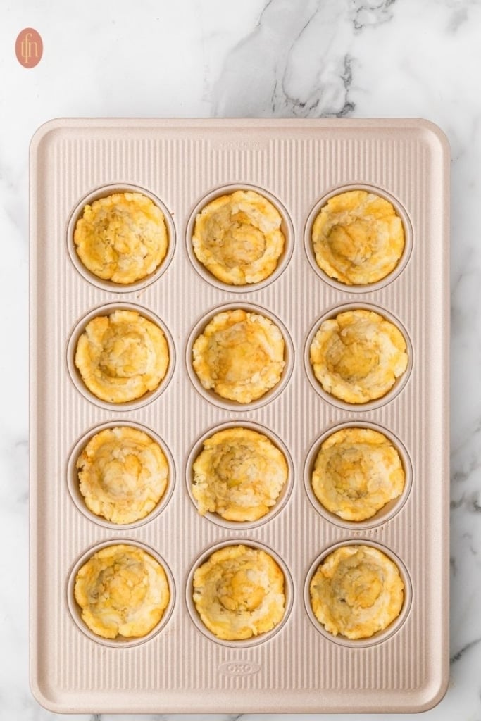 loaded tater tot cup prep on a muffin tin.