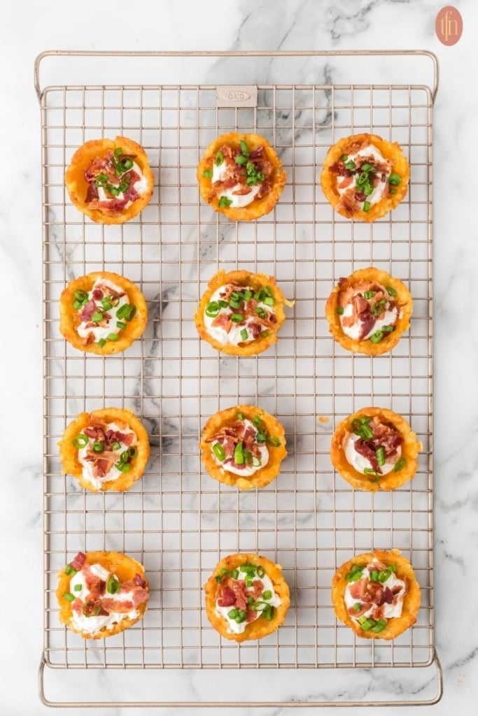 loaded tater tot cups on a wire cooling rack.