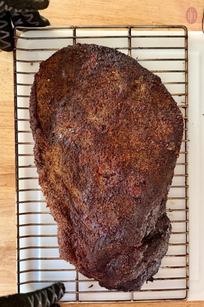 seasoned beef brisket resting on a wire cooling rack.