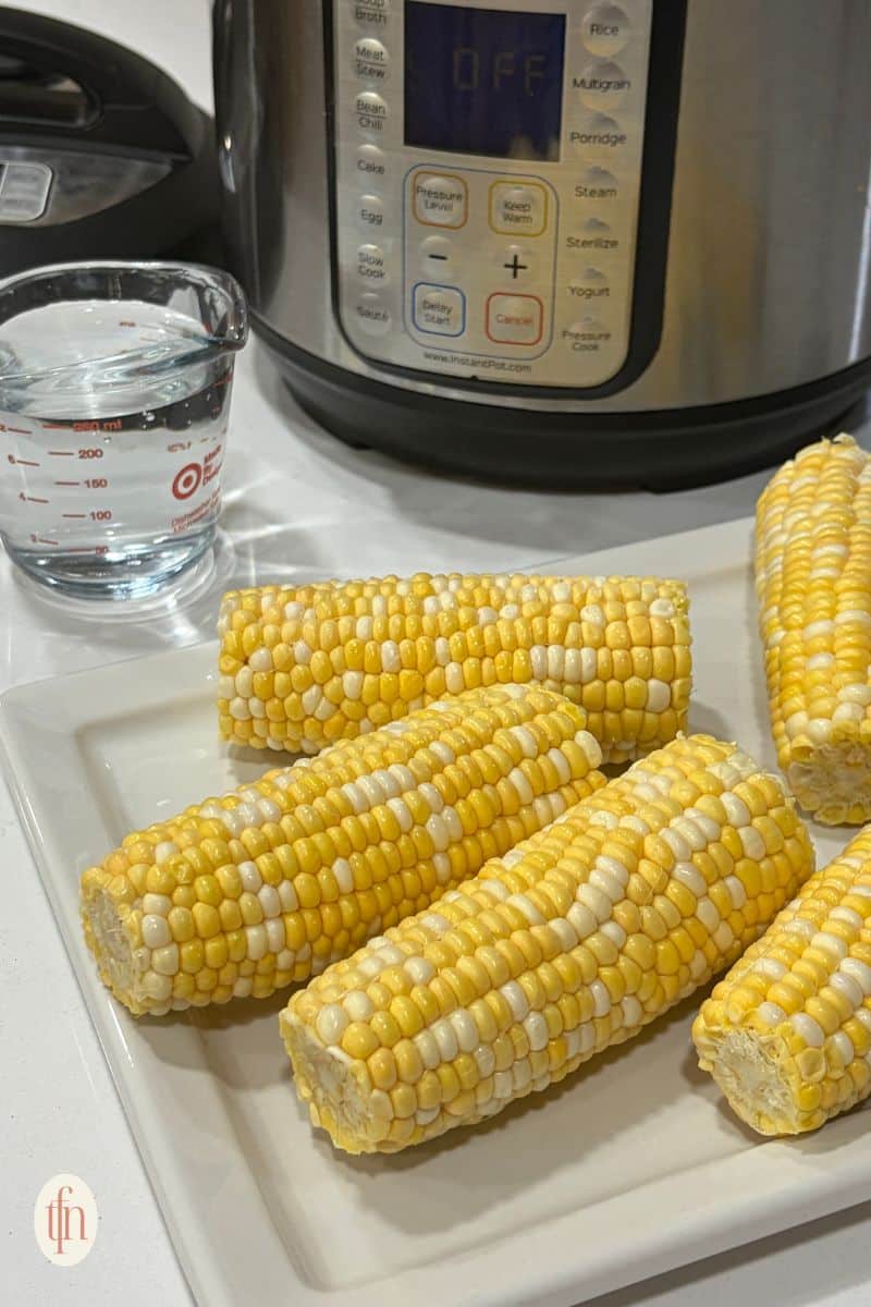 corn on the cob resting on a white serving tray.