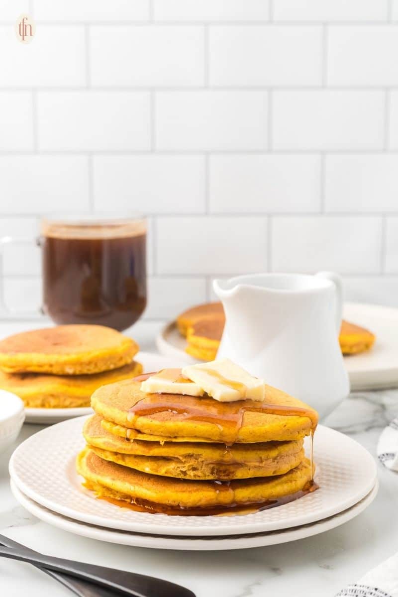 a plate of pumpkin pancakes drizzled with syrup.