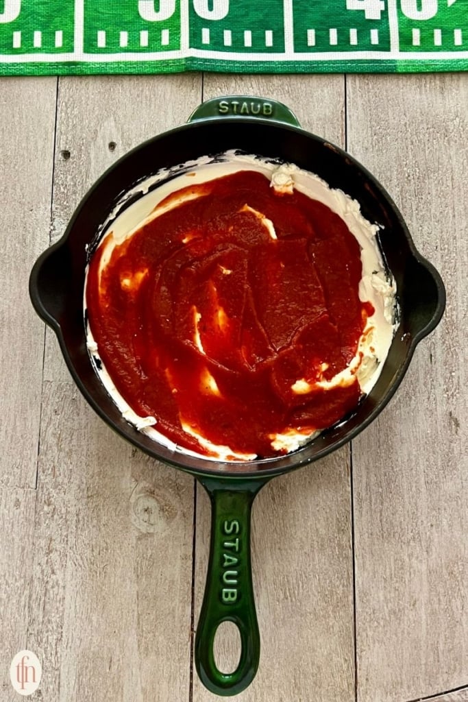 marinara sauce over cream cheese in skillet.