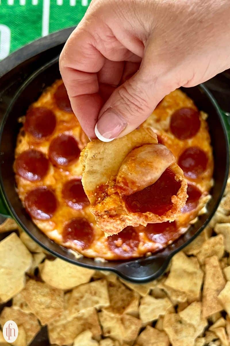 dipping chip in pepperoni dip.